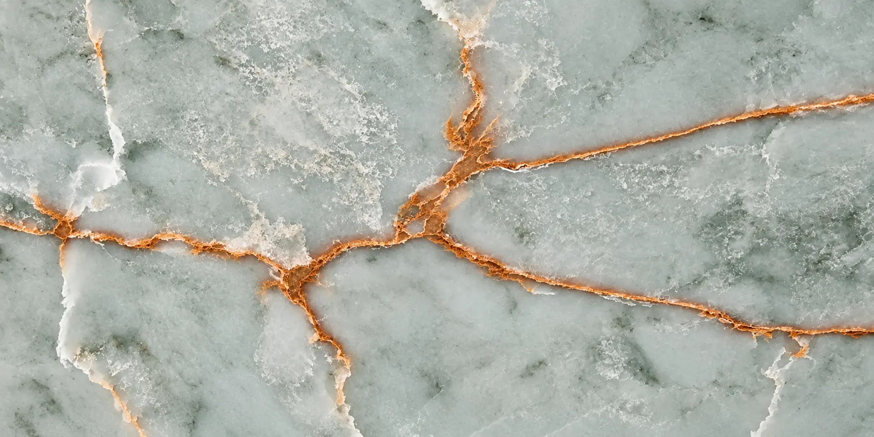 Detailed close-up of intersecting white and copper-gold veins on pale green Green Gold Onyx quartz.