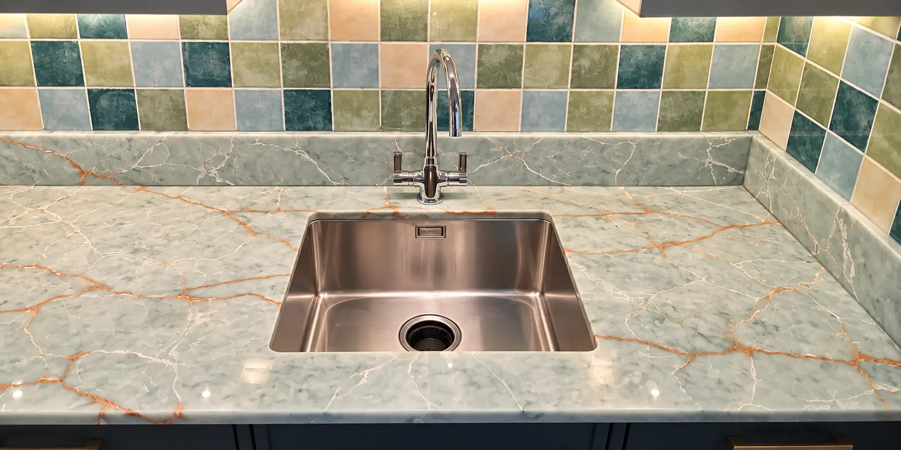 Green Gold Onyx quartz worktop fitted around an undermount stainless-steel sink with a matching short upstand.